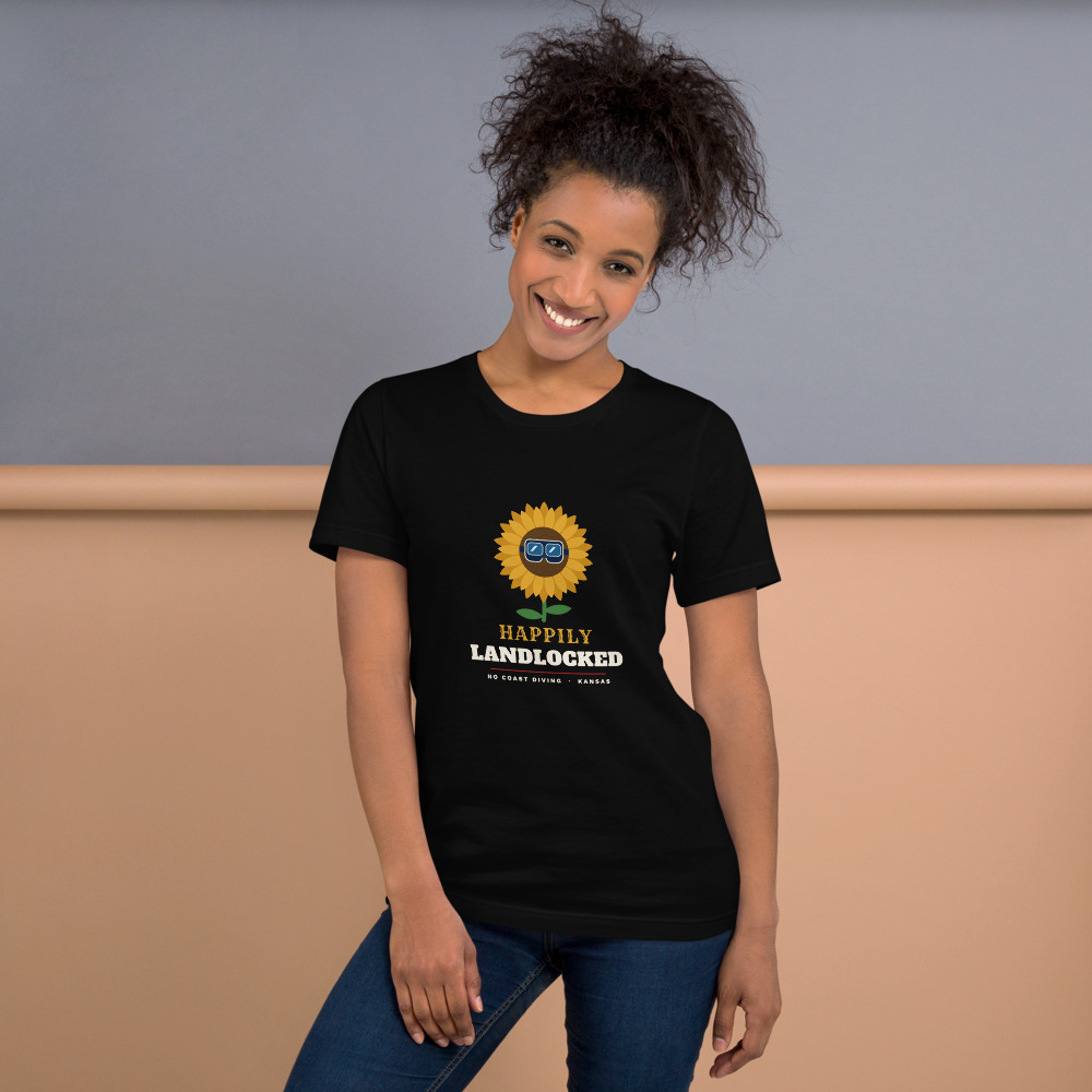 Person wearing a black Happily Landlocked t-shirt with a sunflower wearing a dive mask